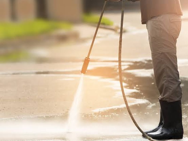Pressure washing a paved surface in Sydney, backlit spray